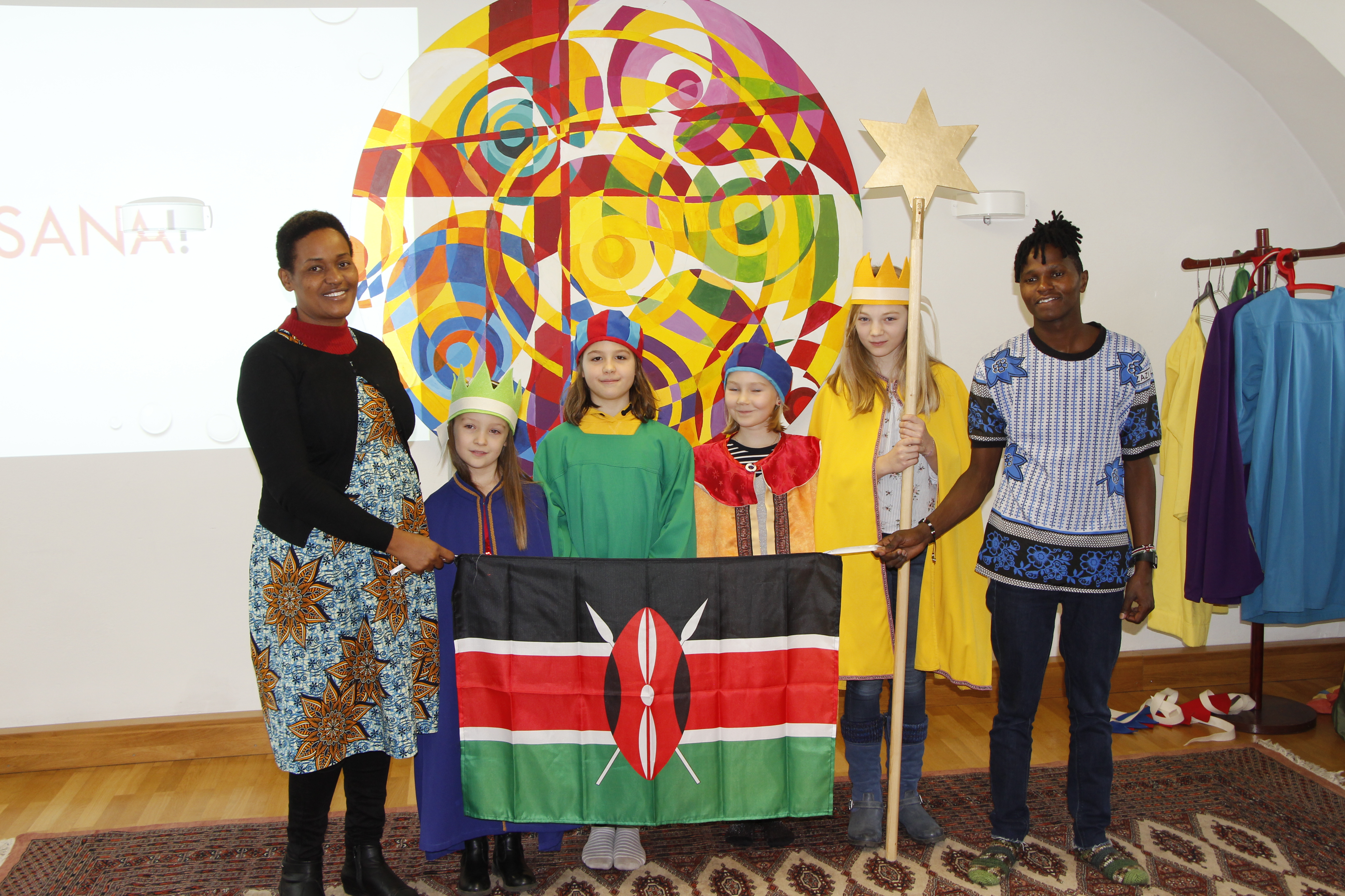 Gruppenfoto einer Sternsingergruppe mit den Projektparter/innen. Letzere halten die kenianische Flagge.