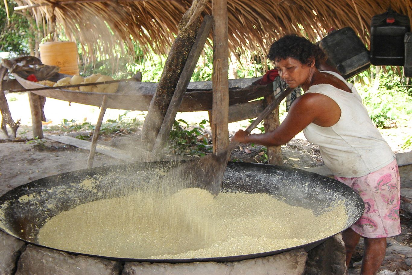 Eine Frau röstet gemahlene Maniokwurzeln in der Pfanne. Die Wurzel wurde schon vor Jahrhunderten von indigenen Völkern kultiviert und ist heute ein Grundnahrungsmittel in ganz Brasilien.