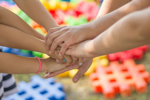 Mehrere Kinder haben ihre Hände übereinander in die Mitte zusammengelegt.