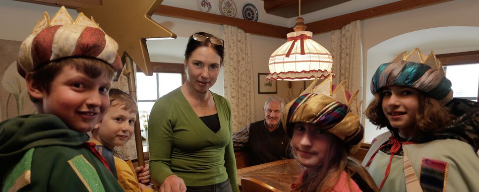 Credit: Leodolter Eine Sternsingergruppe besucht gerade eine Familie zuhause. Sie stehen in der Küche.